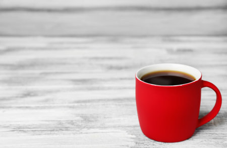 Red ceramic cup with hot aromatic coffee on tableの写真素材