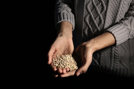 Poor woman holding grains in hands on dark background, closeupの写真素材