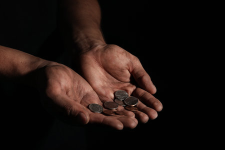 Poor man with coins on dark background, closeupの写真素材