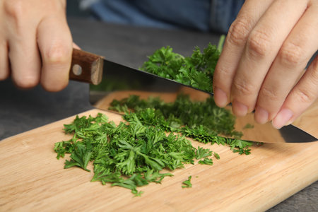 Woman cutting fresh green parsley on wooden board, closeupの写真素材