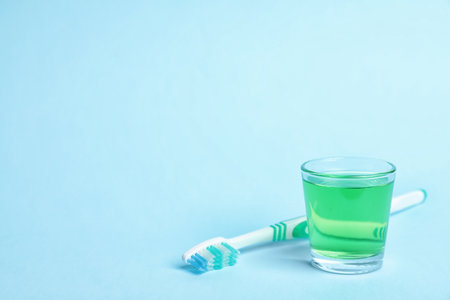 Glass with mouthwash, toothbrush and space for text on color background. Teeth hygieneの写真素材