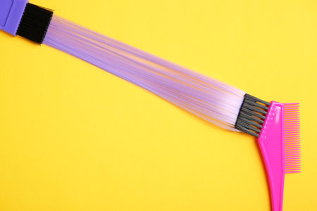 Flat lay composition with strand of hair and brushes on color background. Space for textの写真素材