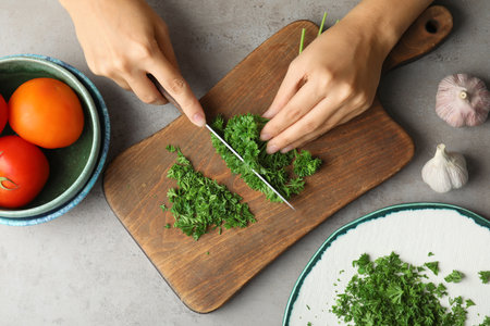 Woman cutting fresh green parsley on wooden board, top viewの写真素材