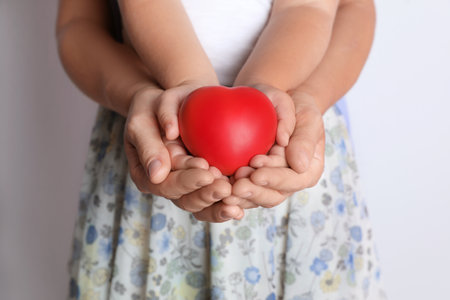 Adult and child hands holding heart on light background, closeup. family conceptの写真素材