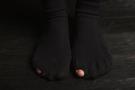 Poor person in shabby socks on wooden floor, closeupの写真素材