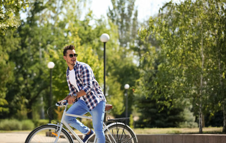 Handsome young hipster man riding bicycle in parkの写真素材