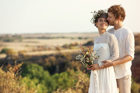 Happy newlyweds with beautiful field bouquet outdoorsの写真素材