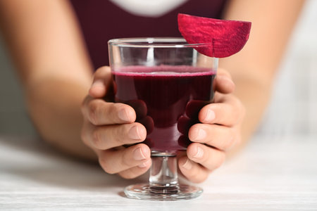 Woman with glass of beet smoothie at table, closeupの写真素材