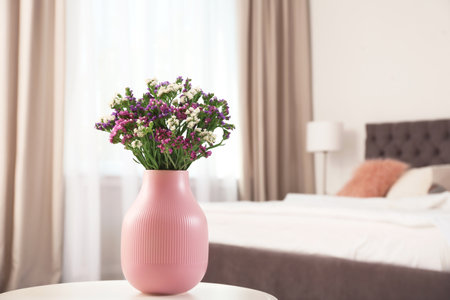 Beautiful flowers in vase and space for text on blurred background. element of interior design