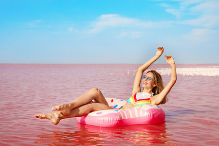 Beautiful woman on inflatable ring in pink lakeの写真素材