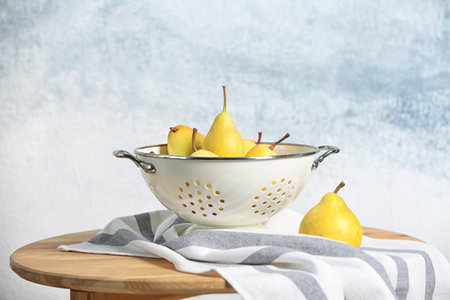 Colander with pears on table against color backgroundの写真素材