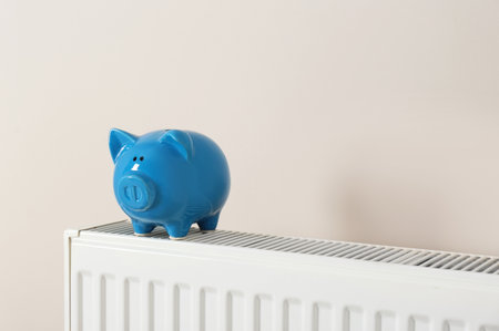 Piggy bank on heating radiator against light backgroundの写真素材