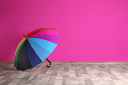 Beautiful open umbrella on floor near color wall with space for designの写真素材