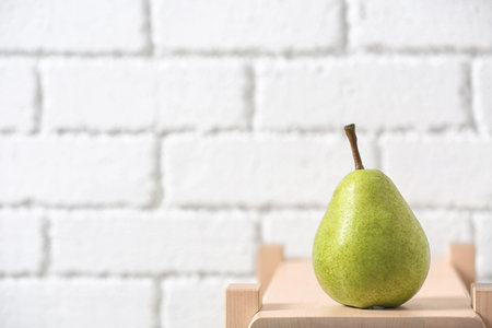 Ripe pear on wooden shelf against blurred background. Space for textの写真素材