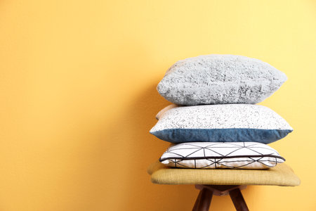 Chair with many different pillows and space for text on color backgroundの写真素材