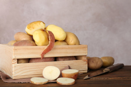 Fresh organic potatoes in wooden crate on tableの写真素材