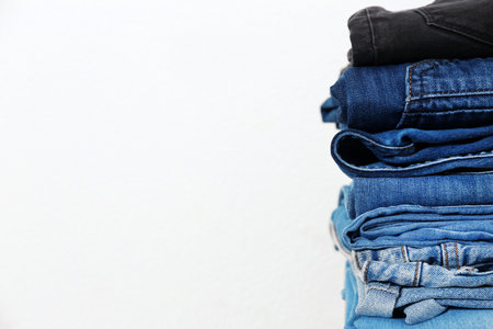 Stack of different jeans against white background. Space for textの写真素材