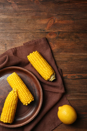 Flat lay composition with corn cobs and lemon on wooden background. Space for textの写真素材