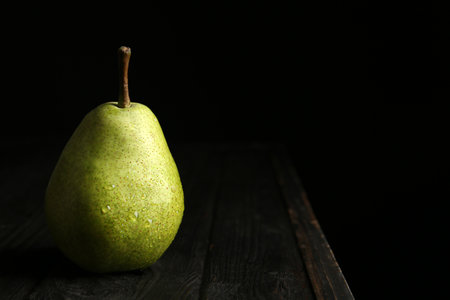 Ripe pear on wooden table against dark background. Space for textの写真素材