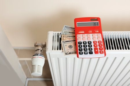 Calculator and money on heating radiator indoorsの写真素材
