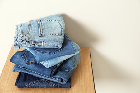 Stack of different jeans on table against light background. Space for textの写真素材