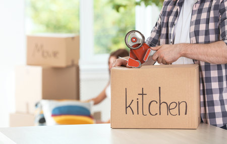 Man packing moving box indoors, closeup. Space for textの写真素材