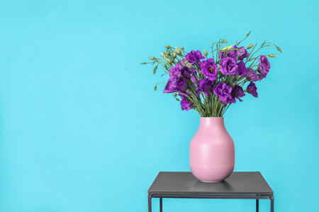 Beautiful bouquet of purple eustoma flowers in vase and space for text on color backgroundの写真素材