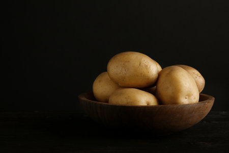 Fresh organic potatoes in bowl and space for text on black backgroundの写真素材
