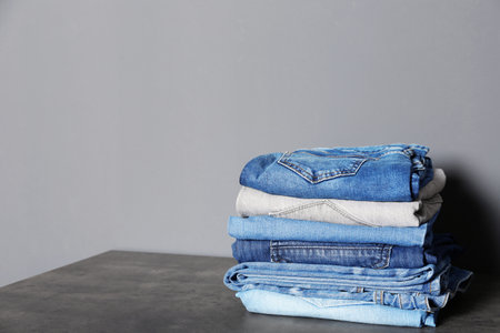 Stack of different jeans on table against gray background. Space for textの写真素材