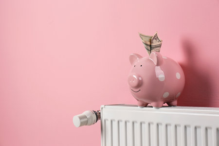 Heating radiator and piggy bank with money on color background. Space for textの写真素材