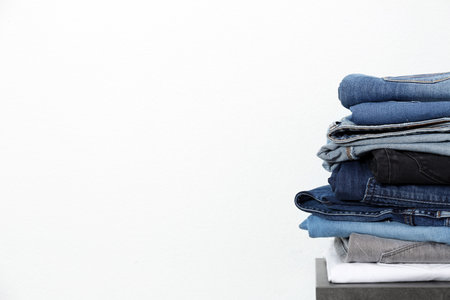 Stack of different jeans on table against white background. Space for textの写真素材
