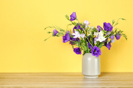 Vase with beautiful flowers on table against color background. Space for textの写真素材