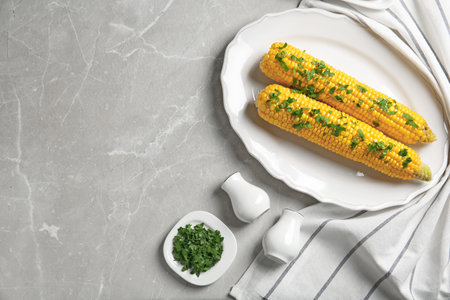 Plate with delicious boiled corn cobs and parsley on light table, top view. Space for textの写真素材
