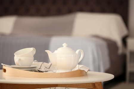 Tray with tea set on table against blurred backgroundの写真素材