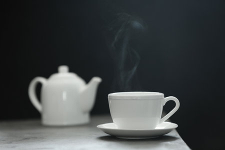 Cup of tea and saucer on table against dark backgroundの写真素材