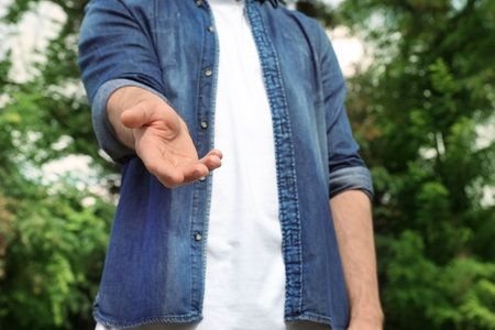 Man giving helping hand on blurred background outdoorsの写真素材