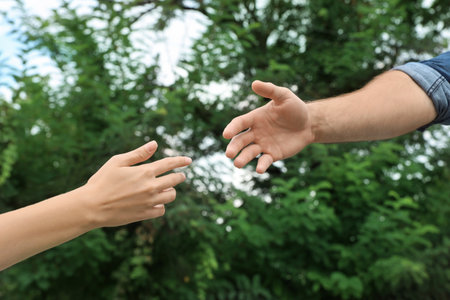 Man and woman giving each other hands outdoors. Concept of support and helpの写真素材