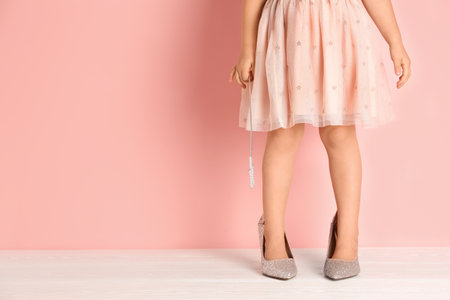 Little girl in oversized shoes near color wall with space for text, closeup on legsの写真素材