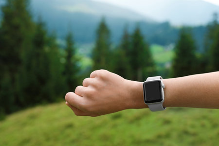 Woman checking smart watch with blank screen in wilderness, closeupの写真素材