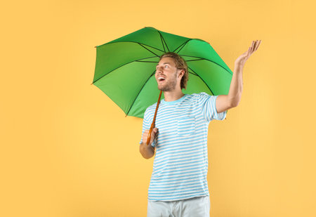 Man with green umbrella on color backgroundの写真素材