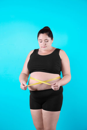 Fat woman with measuring tape on color background. weight lossの写真素材
