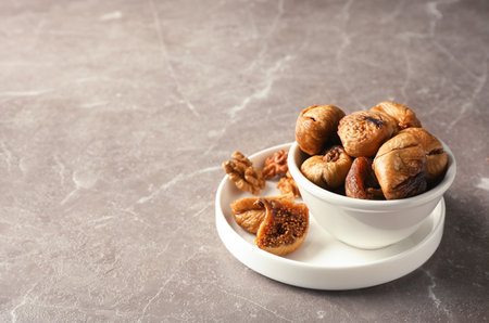 Dishware with dried figs on gray background. Space for textの写真素材