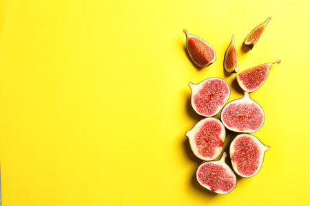 Cut ripe figs on color background, top view. Space for textの写真素材