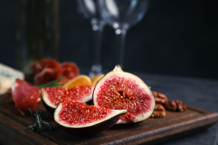 Wooden board with ripe fig slices on table against dark background, closeupの写真素材