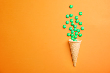 Flat lay composition with candies and ice cream cone on color background. Space for textの写真素材