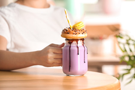 Woman with mason jar of delicious milk shake at table, closeupの写真素材