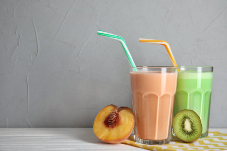 Glasses of tasty milk shakes and fresh fruits on table. Space for textの写真素材