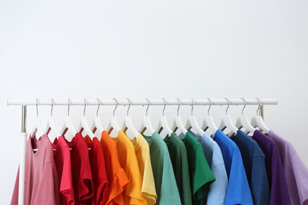 Rack with bright clothes on white background. Rainbow colorsの写真素材