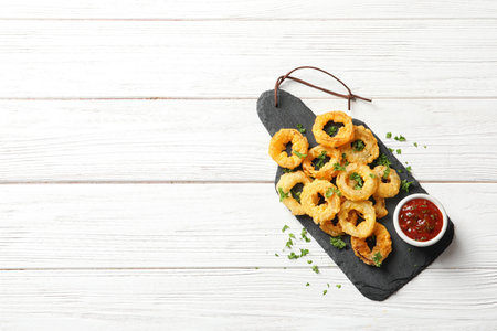 Homemade crunchy fried onion rings with tomato sauce on wooden table, top view. Space for textの写真素材