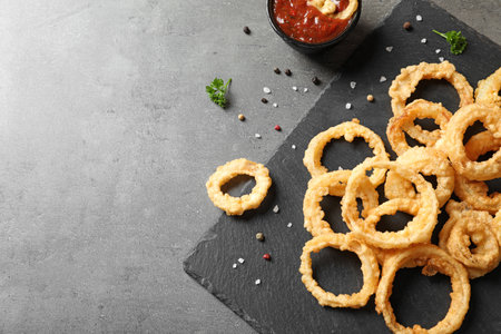 Homemade crunchy fried onion rings with tomato sauce on table, top view. Space for textの写真素材